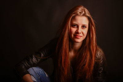 Portrait of beautiful woman sitting against black background