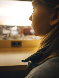 Girl looking through window while sitting at airport