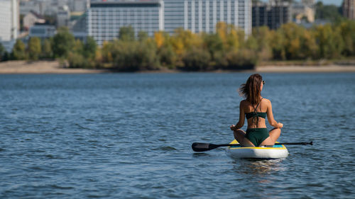 Woman sitting on paddleboard in lake