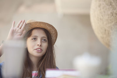 Teenage girl wearing hat looking away at sidewalk cafe