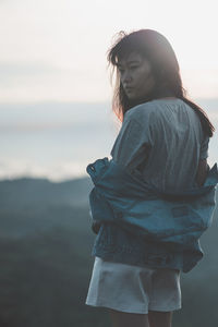 Side view of woman standing against sky during sunset