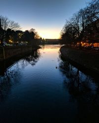 Reflection of silhouette trees on water against sky