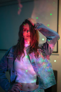 Portrait of woman standing against illuminated wall