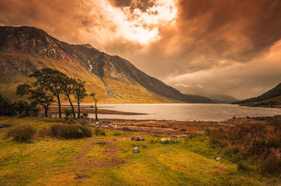 Scenic view of lake and mountains against sky during sunset