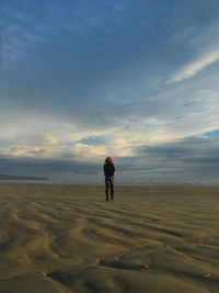 Rear view of man standing on land against sky during sunset