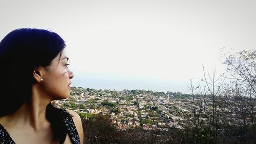Young woman in city against clear sky