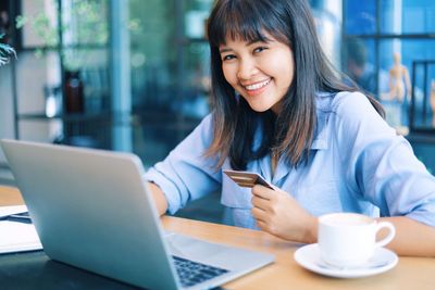 Portrait of smiling businesswoman holding credit card in office