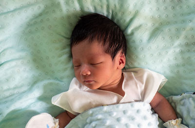 Baby sleeping on turquoise mattress