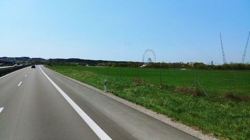 Road amidst field against clear sky