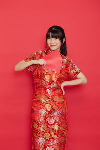 Portrait of smiling young woman against red background