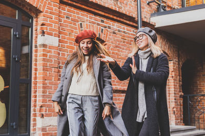 Portrait of smiling friends standing against building