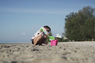 Boy with chocolate on sand at beach against sky