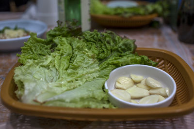 Lettuce and garlic in plastic container on table