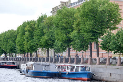 Boats in canal by trees against sky