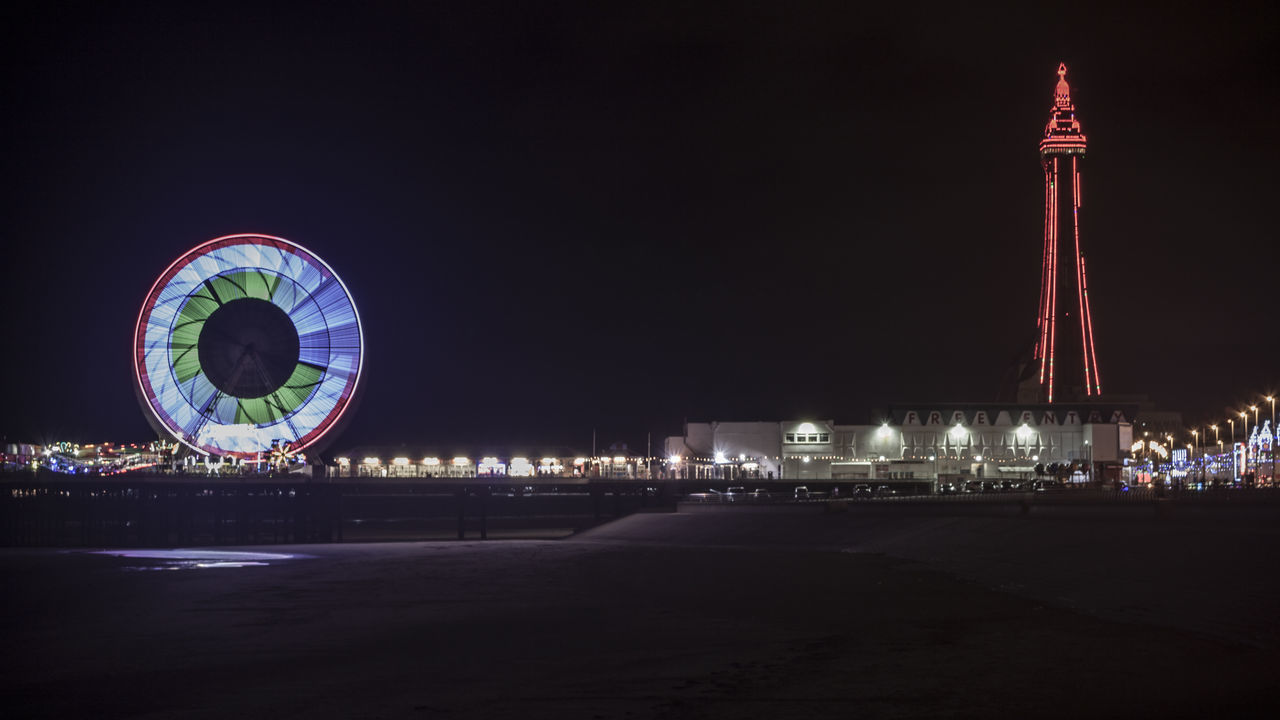 ILLUMINATED FERRIS WHEEL IN CITY AT NIGHT