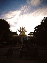 Low angle view of trees against cloudy sky