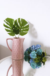 Leaves in vase by flowers on table