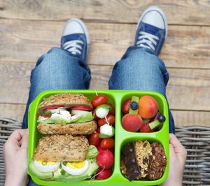 Low section of man sitting with lunch box