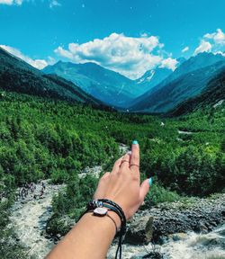 Cropped hand of woman pointing towards mountain range