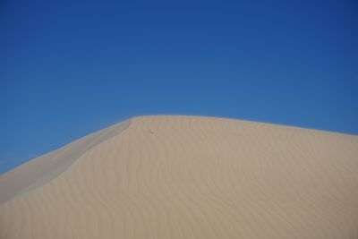 Sand dunes against clear blue sky