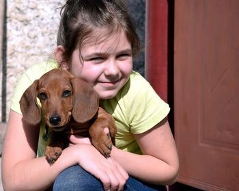 Portrait of young girl with dog at home