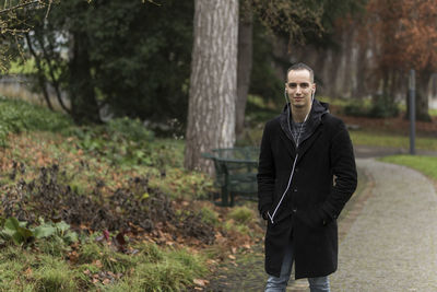 Portrait of young man standing on tree trunk