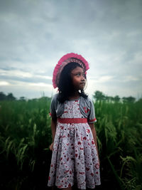 Girl standing on field against sky