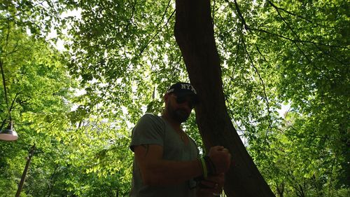 Low angle view of man standing by tree in forest