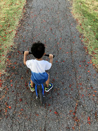 Rear view of boy riding bicycle on road