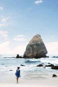 Woman standing at beach against sky