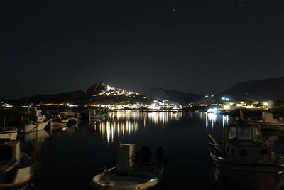 Illuminated boats moored in lake against sky at night