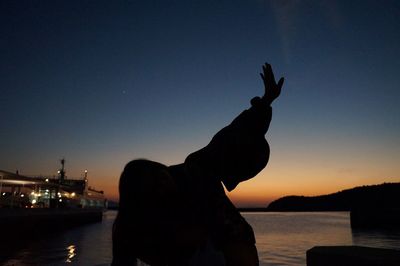 Silhouette of woman on beach against sky at sunset