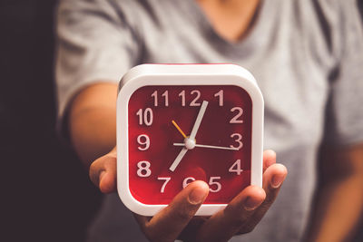 Midsection of woman showing alarm clock