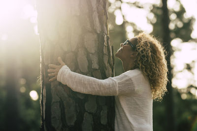 Smiling woman embracing tree trunk