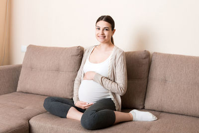 Portrait of smiling young woman sitting on sofa at home