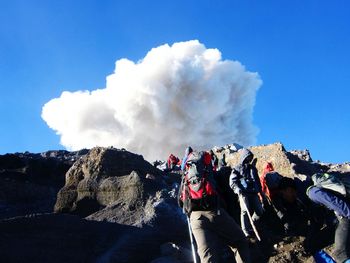 Panoramic view of people on rock against sky