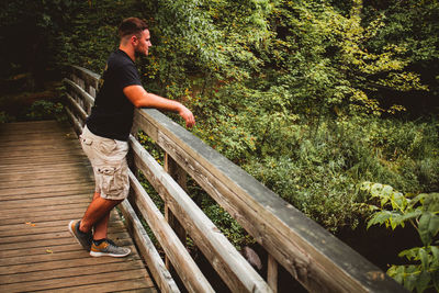 Side view of young man on plants against trees