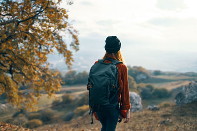 Rear view of man standing on rock against sky