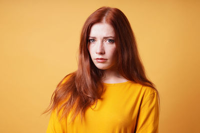 Portrait of young woman against yellow background