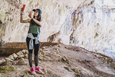 Full length of woman photographing on rock