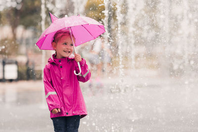 Cute girl holding umbrella in rain