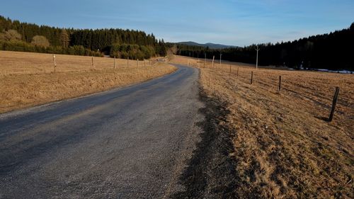 Road amidst field against sky