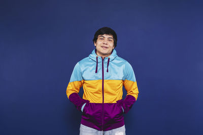 Portrait of young man standing against blue background