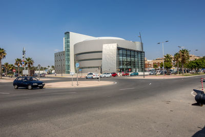 Cars on road by buildings against clear sky in city