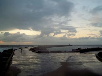 Scenic view of sea against cloudy sky at sunset