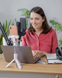 Portrait of young woman using laptop while sitting on table