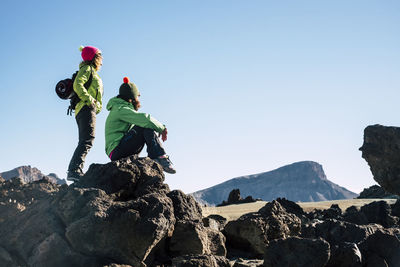 Low angle view of man standing on rock against clear sky