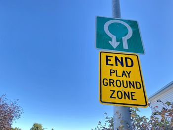 Low angle view of road sign against blue sky