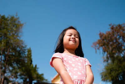 Low angle portrait of woman against clear sky