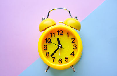 Close-up of yellow clock against wall